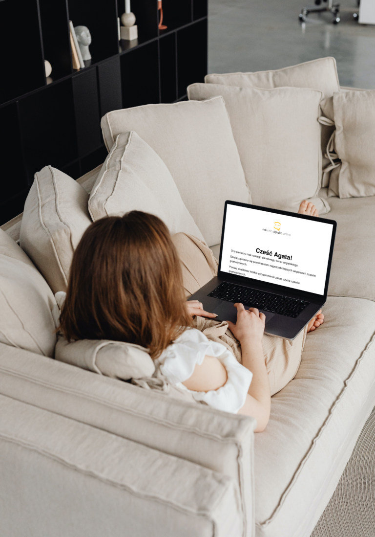 Kobieta leżąca na kanapie i przeglądająca darmowy kurs angielskiego online na ekranie komputera.